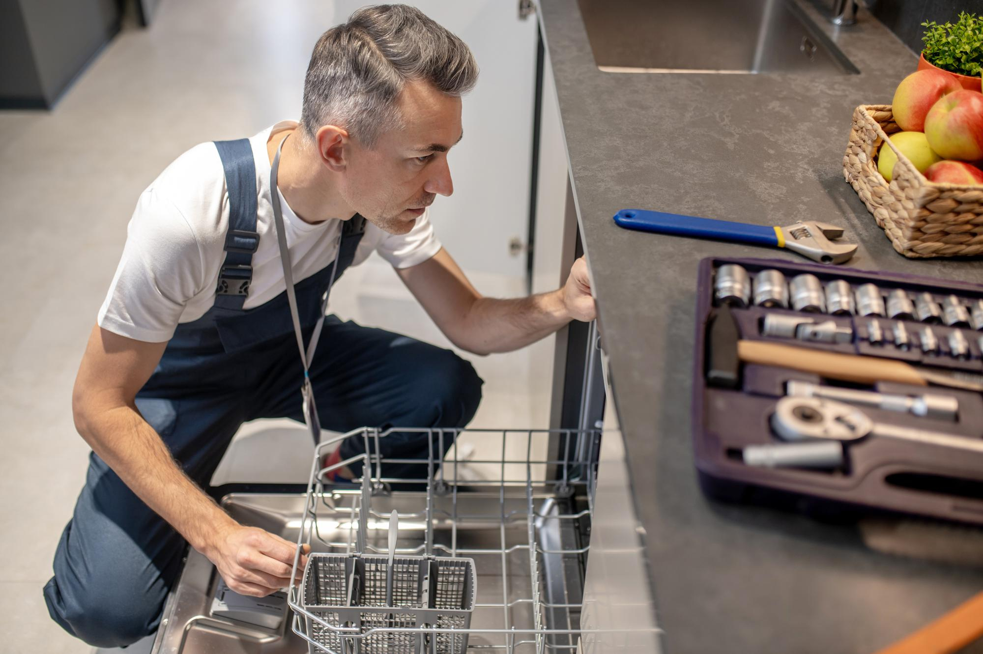 dishwasher-repair-top-view-middleaged-man-crouching-near-open-dishwasher