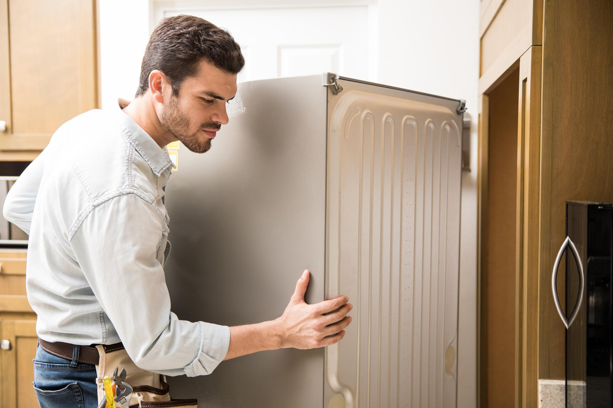 young-man-working-as-electrician-exposing-back-fridge-check-repair-it